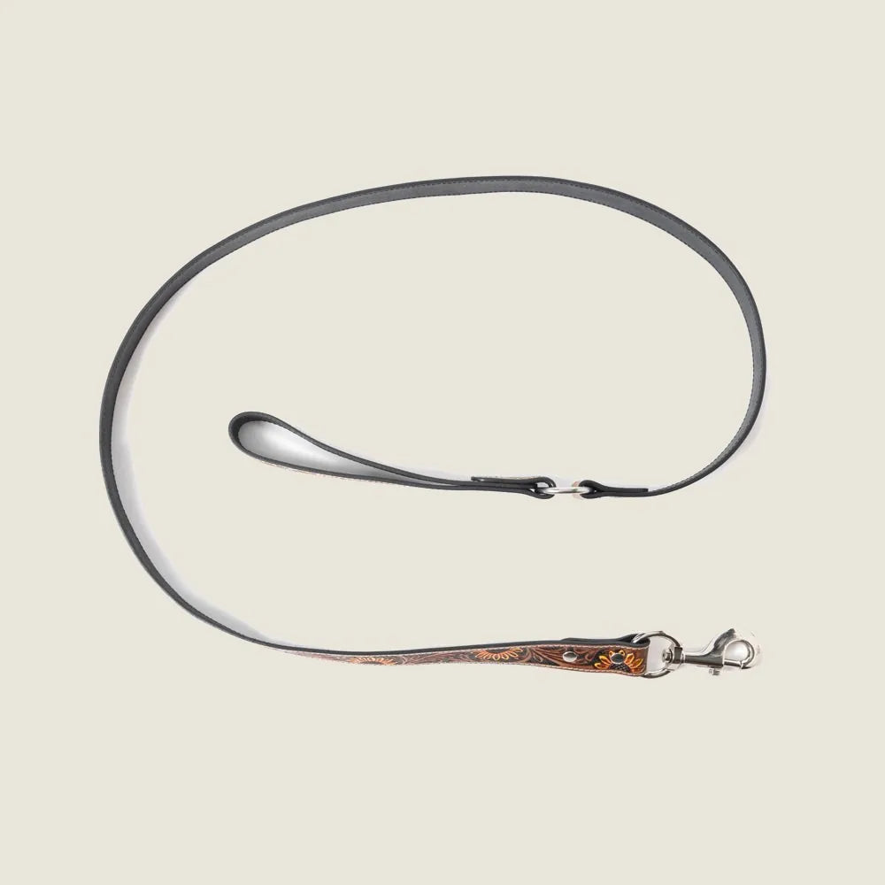 Light brown hand-tooled leather dog leash with floral embossing, braided border, and sturdy silver hardware.