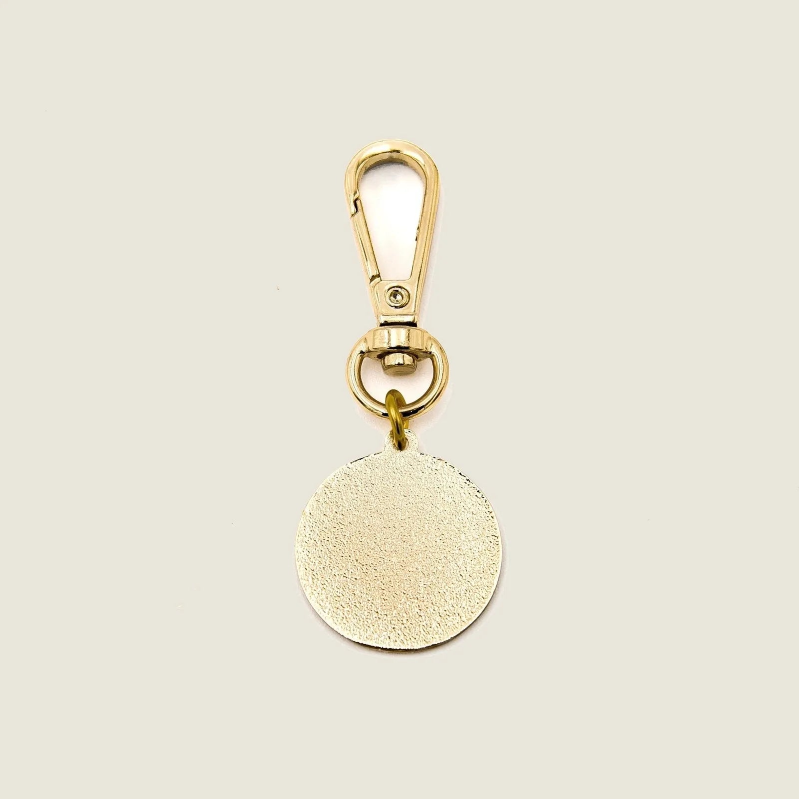 Classic logo charm featuring a light gold circular design with a lobster claw clasp for easy attachment.