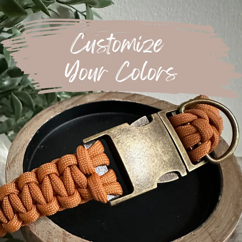 Handmade Cobra Braid collar in orange nylon paracord with a brass side release buckle, set on a wooden dish.