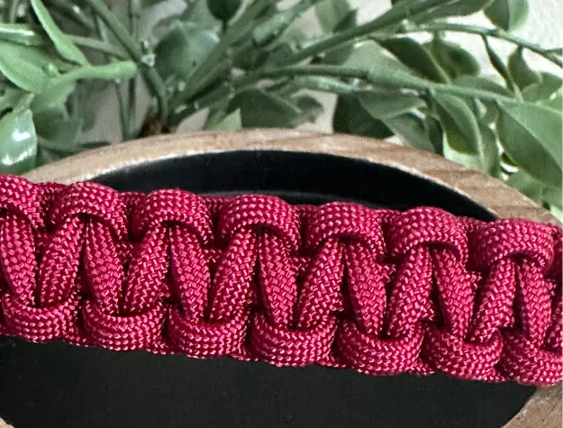 Handwoven maroon cobra braid dog collar made from durable American nylon paracord, resting on a wooden surface.