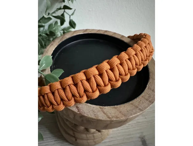Handmade orange Cobra Braid dog collar showcased on a wooden bowl, highlighting durable paracord craftsmanship.
