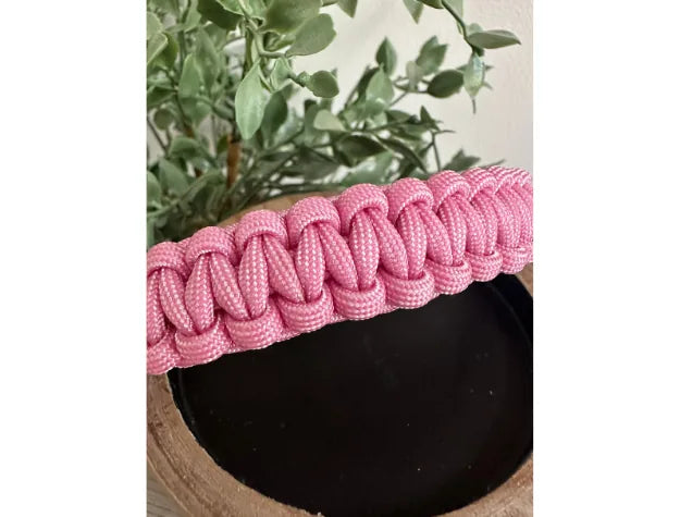 Handmade pink and white striped cobra braid dog collar, showcasing durable nylon paracord against a dark wooden backdrop.
