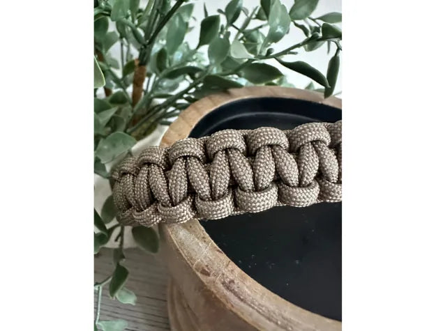 Tan Cobra Braid dog collar made from premium nylon paracord, featuring a handwoven design resting on a wooden surface.