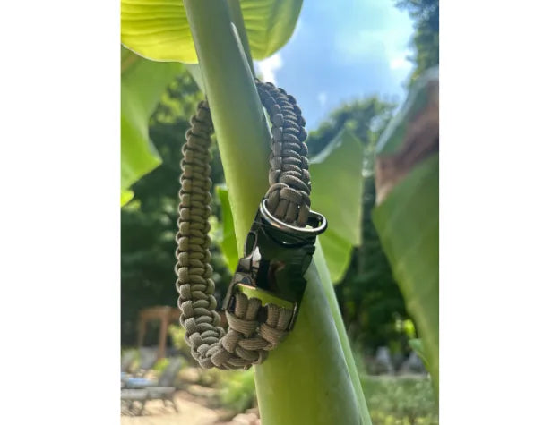 Tan handmade Cobra Braid collar hanging on a green palm leaf, featuring a side-release buckle and braided design.