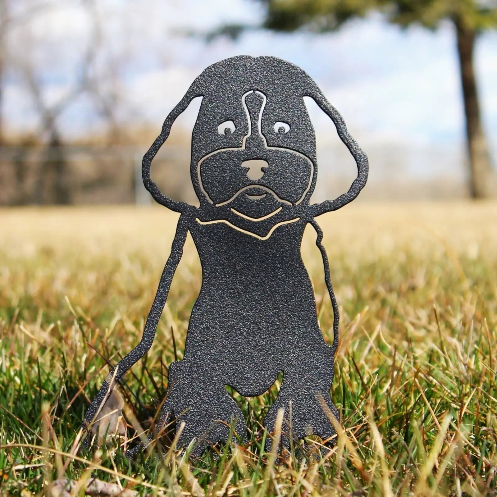 Black metal silhouette of a Cockapoo sitting in grass, showcasing detailed features and craftsmanship.