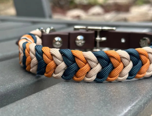Hand-braided dog collar featuring mustard, navy, and light tan nylon paracord with a dark brown adjustable strap.