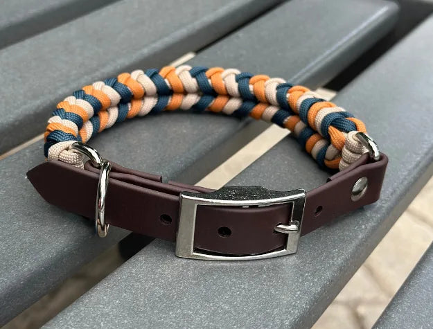 Hand-braided dog collar in mustard, navy, and tan with a dark brown adjustable strap and sturdy D-ring for leash attachment.