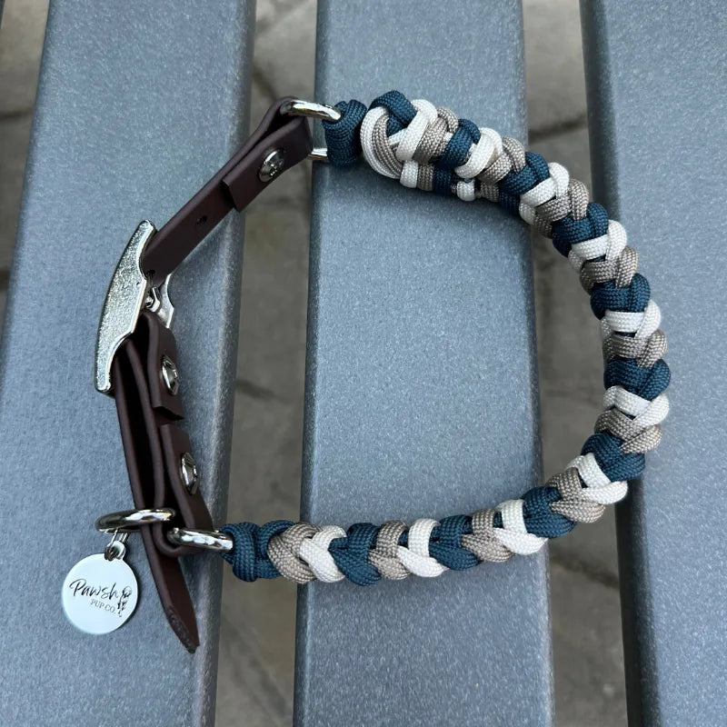 Hand-braided dog collar in navy, tan, and cream with a dark brown strap and nickel plated buckle.