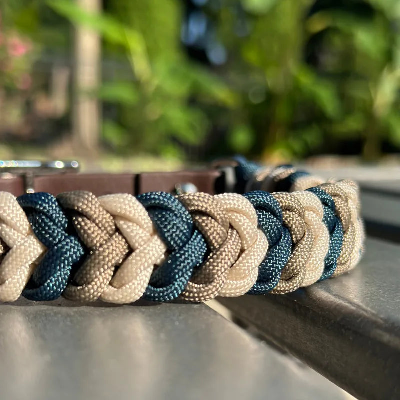 Hand-braided dog collar featuring navy, tan, and cream nylon paracord with a dark brown strap and nickel buckle.
