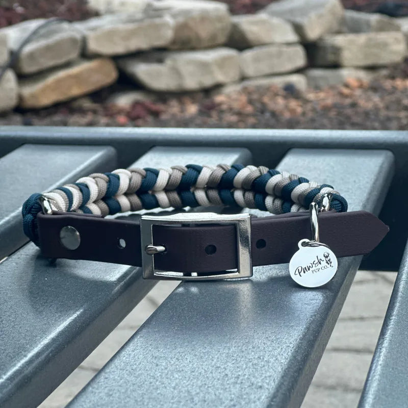Hand-braided dog collar in navy, tan, and cream with a dark brown strap and nickel plated buckle.