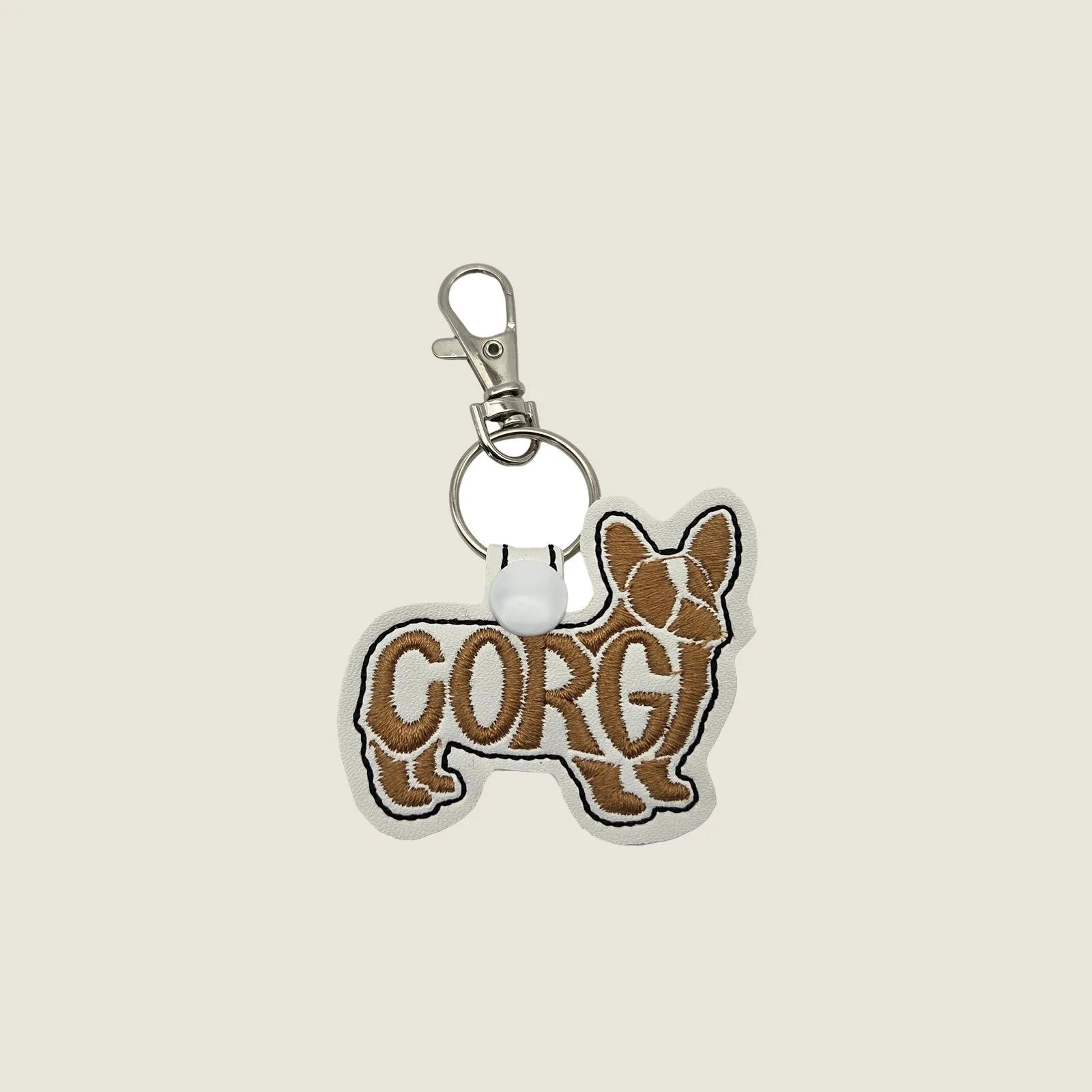 Embroidered Corgi keychain in brown and white with swivel clasp, highlighting the word "CORGI." Ideal for dog lovers.
