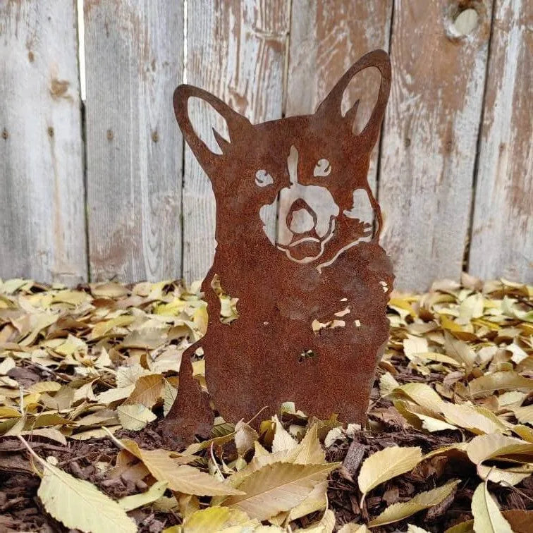 Corgi silhouette in rusted Corten steel, surrounded by autumn leaves, adds a charming touch to garden decor.