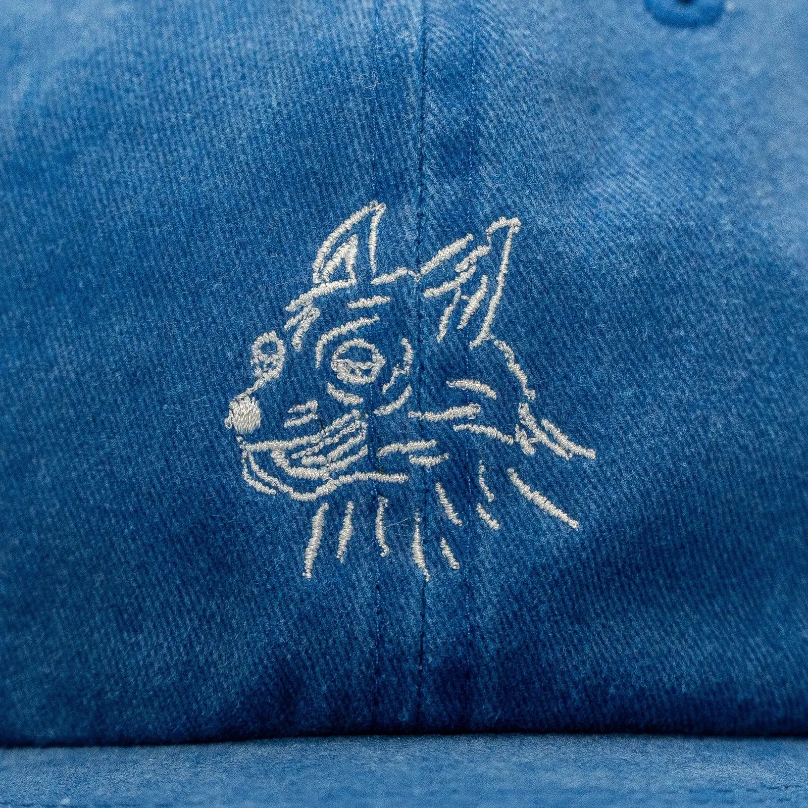 Faded royal blue cap featuring a whimsical embroidered dog face design.