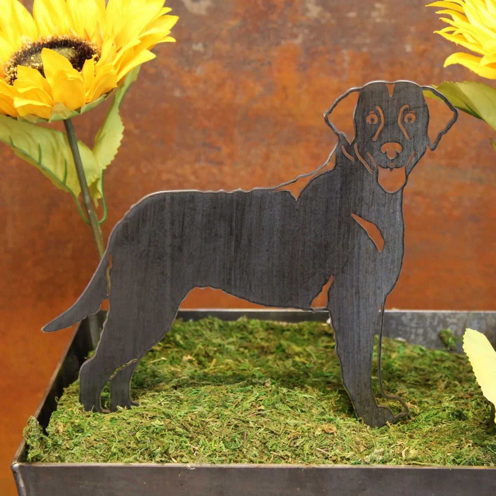 Curly Coated Retriever metal silhouette in matte black, showcasing intricate design, placed in decorative moss arrangement.