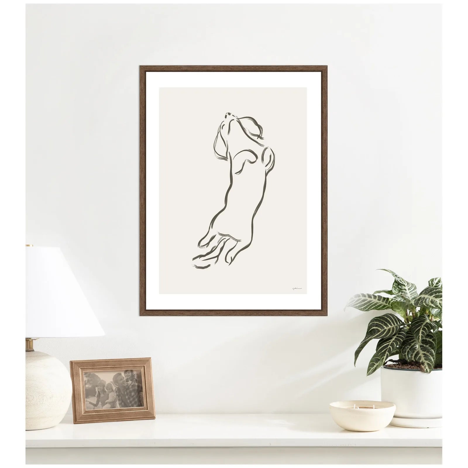 Framed canvas art of a Dachshund dog in a sleek walnut brown frame, hanging on a light-colored wall.