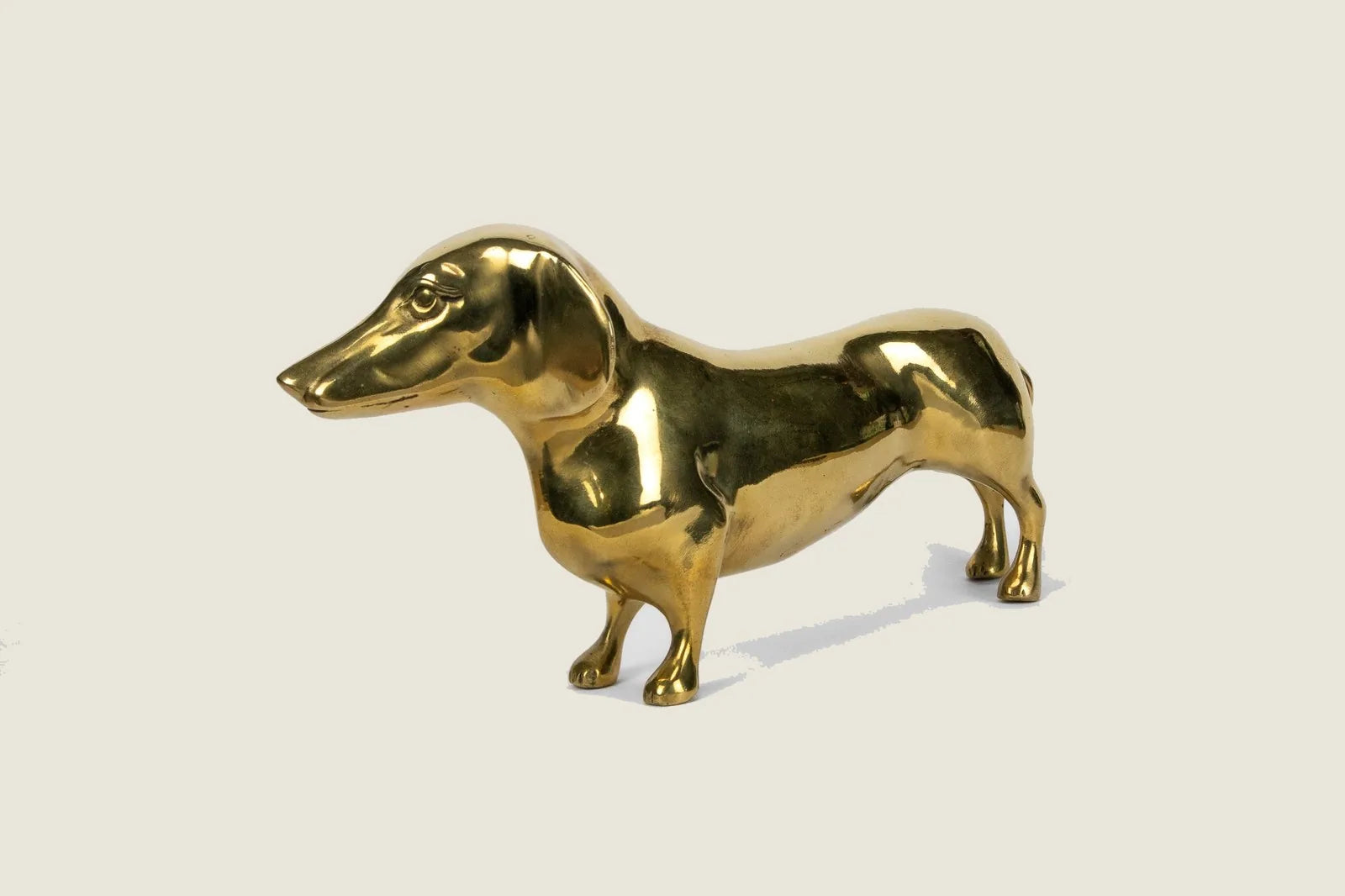 Handcrafted brass dachshund sculpture with a high gloss finish, measuring 10 inches long, perfect for decor.