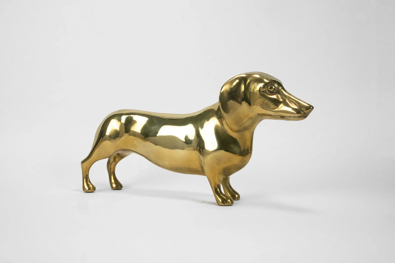 Handcrafted brass Dachshund sculpture with a polished finish, measuring 10 inches long, adding elegance to decor.