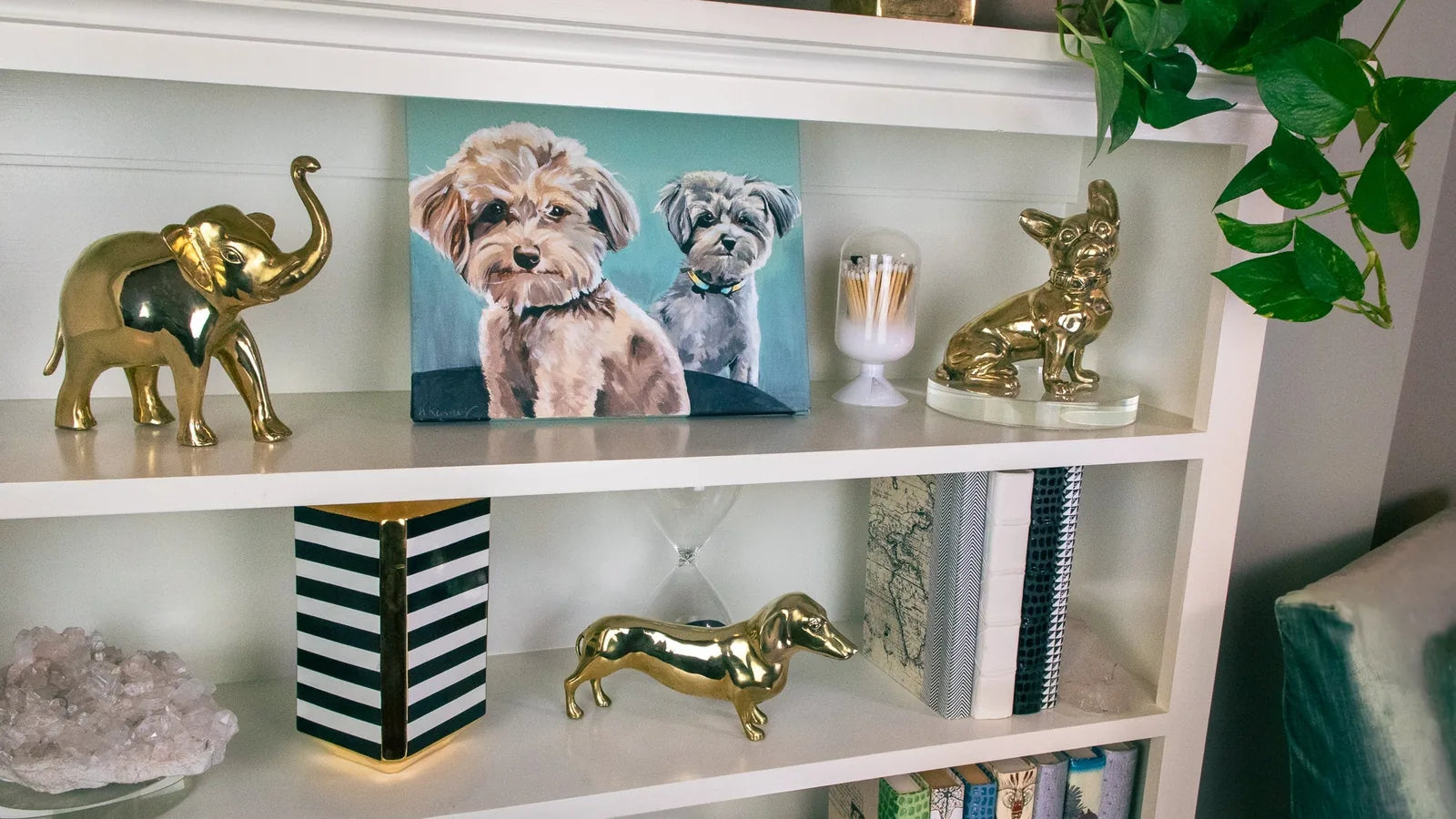 Handcrafted brass Dachshund sculpture, polished with a high gloss finish, situated on a white shelf among decorative items.