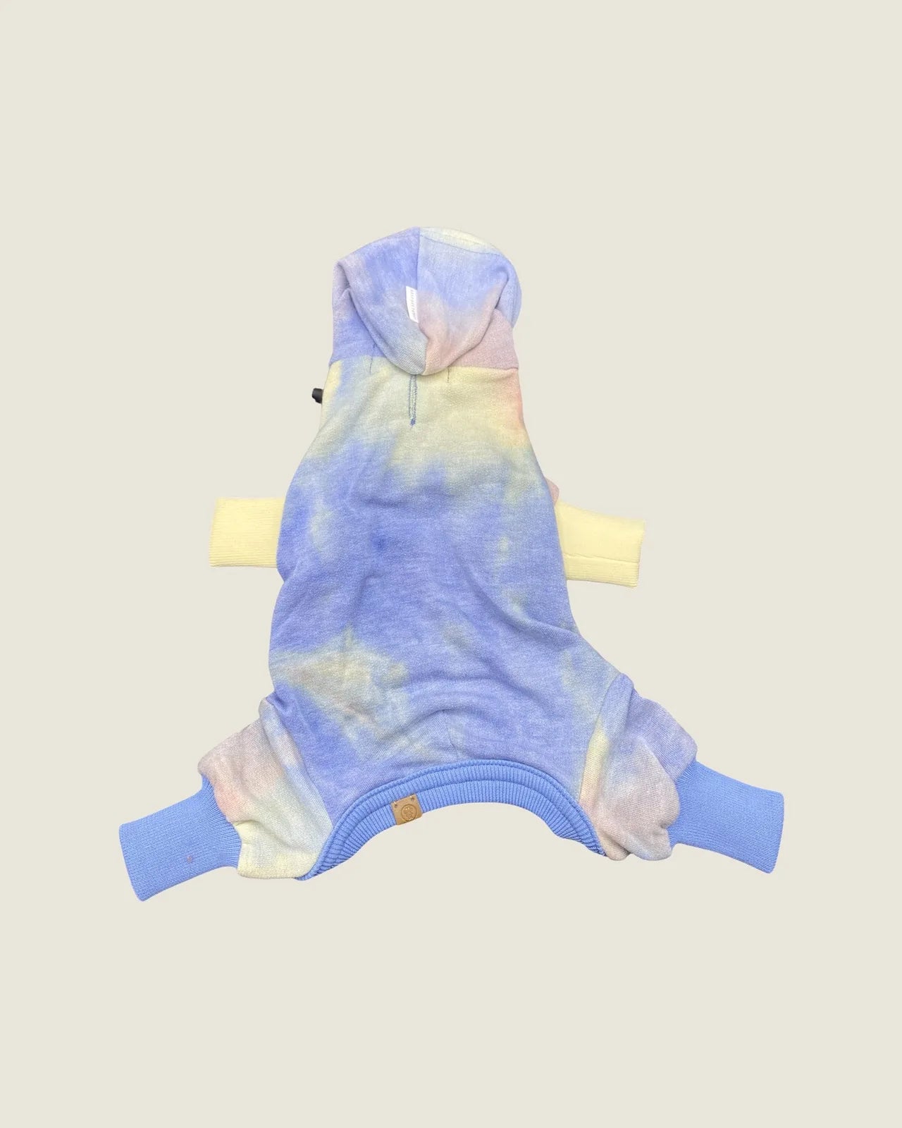 Rainbow tie-dye hooded onesie with soft fabric, featuring light blue hood and vibrant yellow and blue ribbed cuffs.