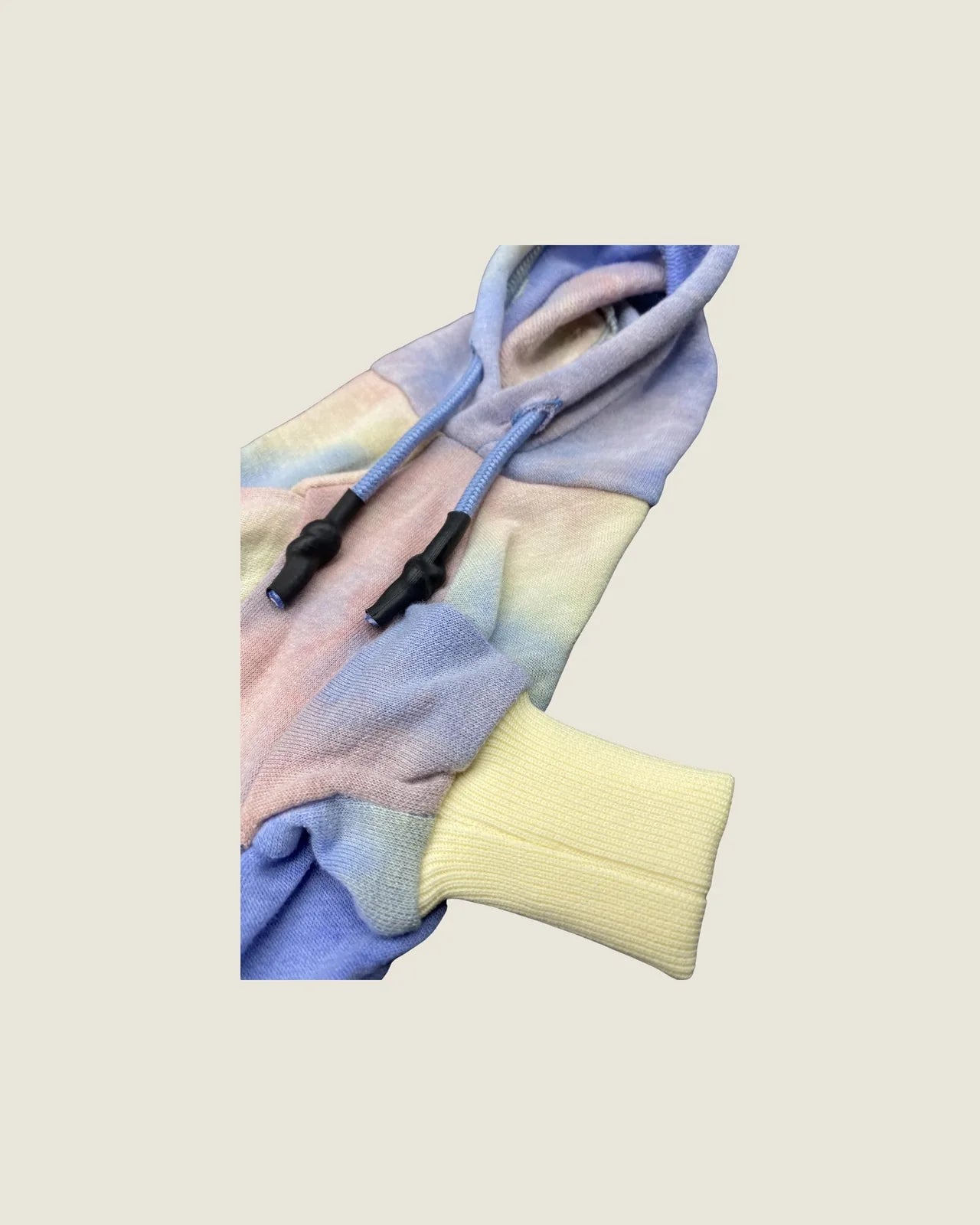 Rainbow tie-dye dog hoodie featuring a light blue drawstring and yellow ribbed cuffs for a secure fit.