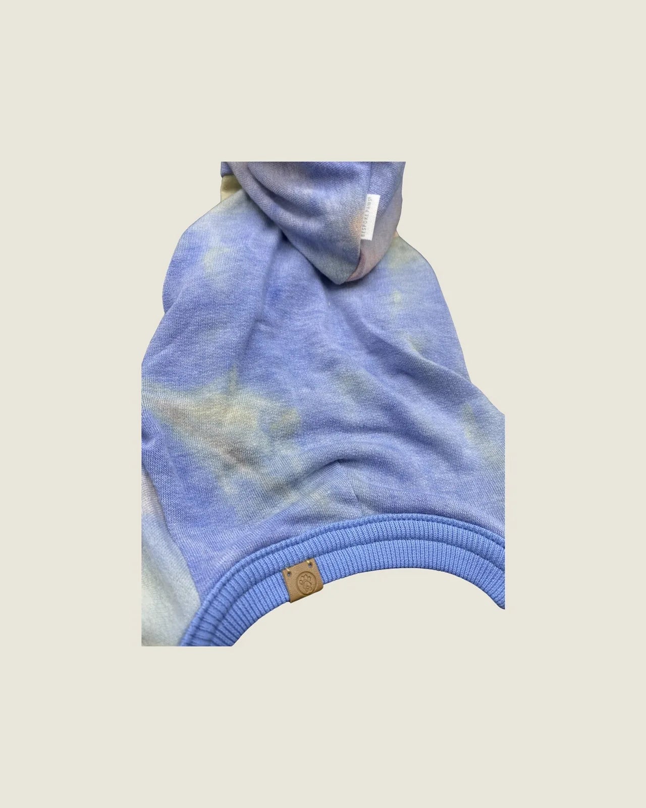 Hooded onesie in soft blue tie-dye fabric with ribbed cuffs, designed for small to medium dogs.