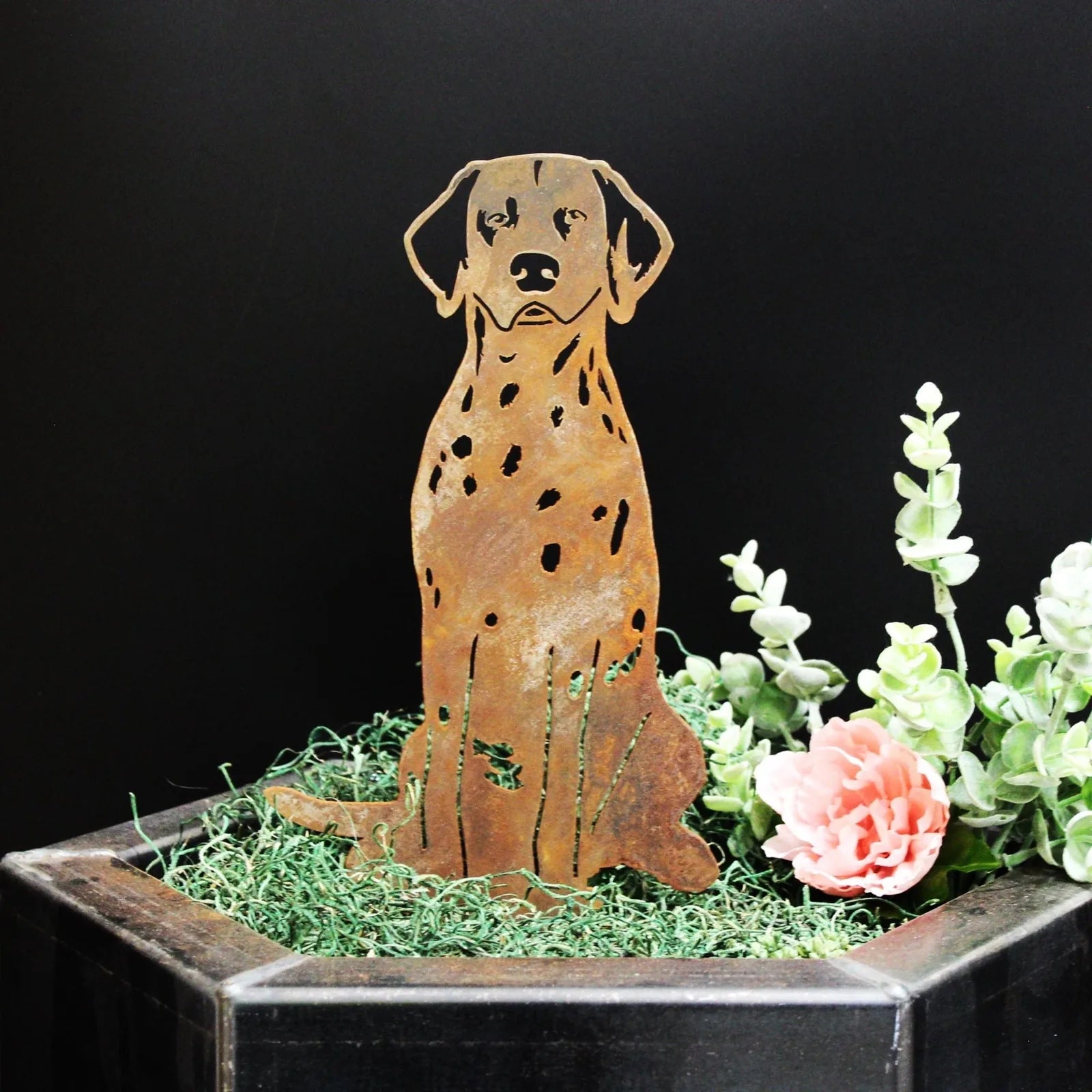 Dalmatian metal silhouette in rust patina, positioned among greenery and flowers in a decorative planter.