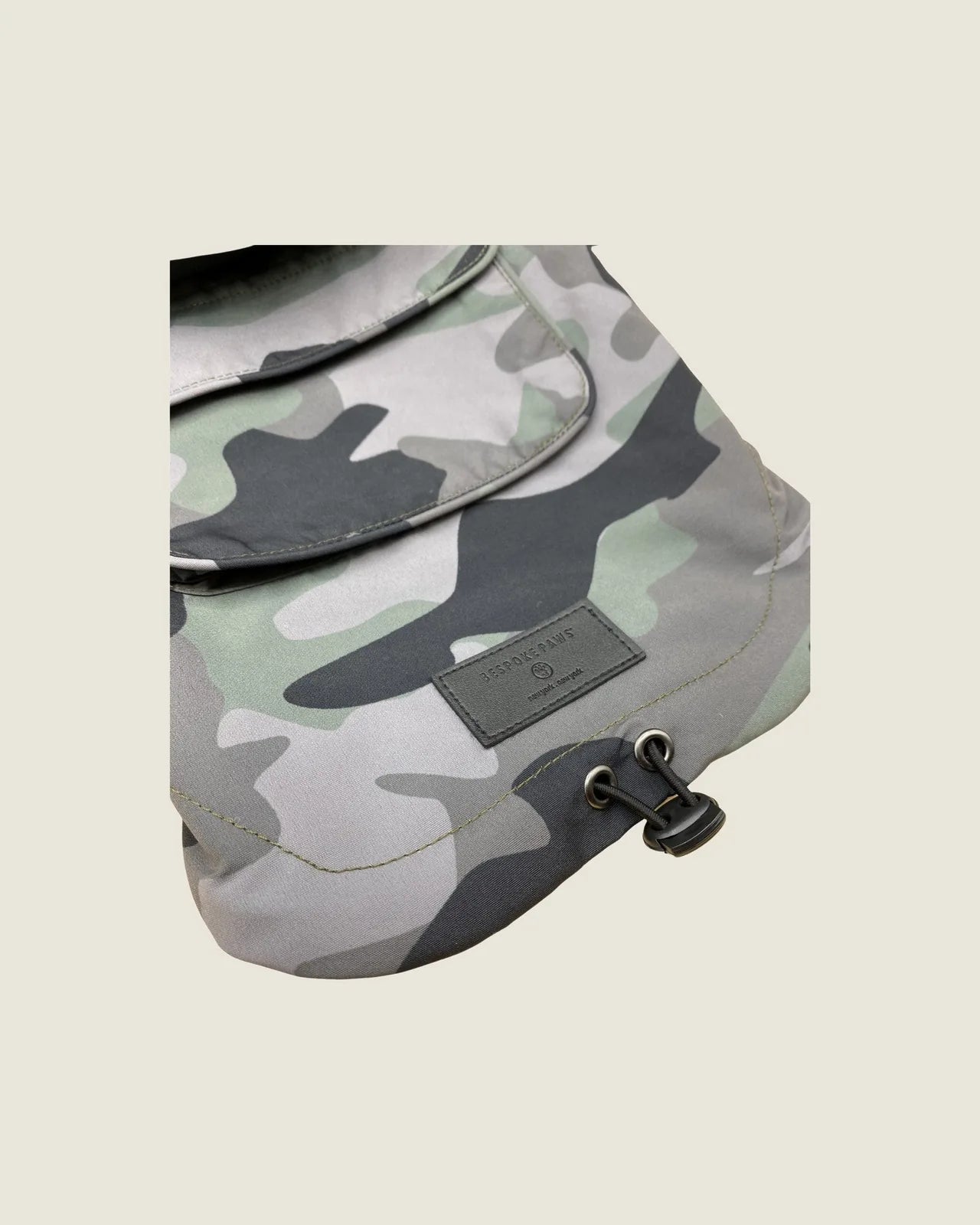 Olive camouflage waterproof dog raincoat with adjustable straps and BESPOKE PAWS logo, designed for comfort and style.