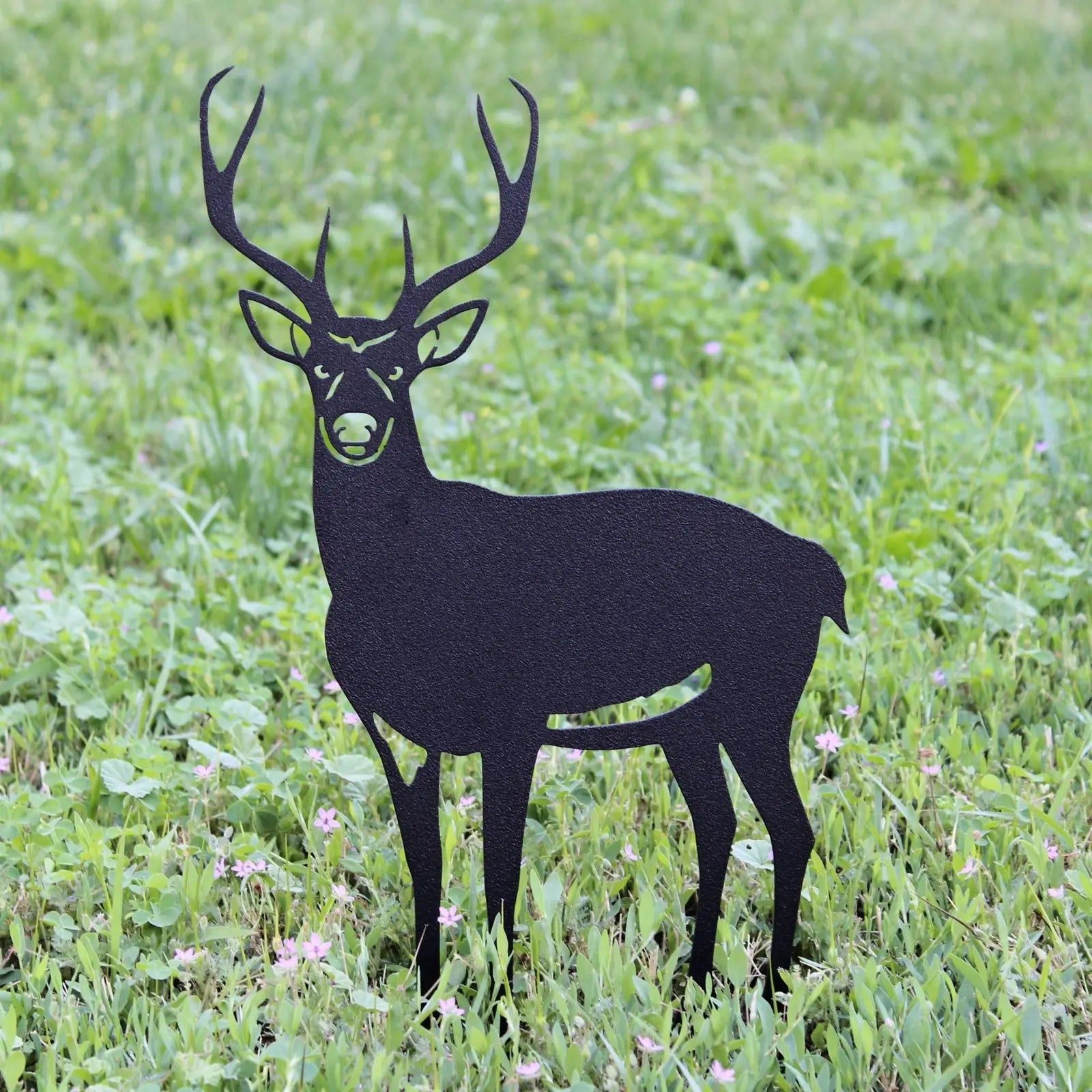 Black metal silhouette of a deer standing on green grass, showcasing intricate antler design and sturdy construction.