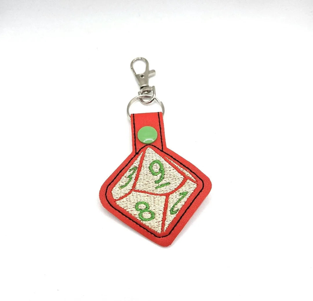Red Dice Keychain featuring a 10-sided die design with green numbers and a snap clasp, ideal for tabletop RPG fans.
