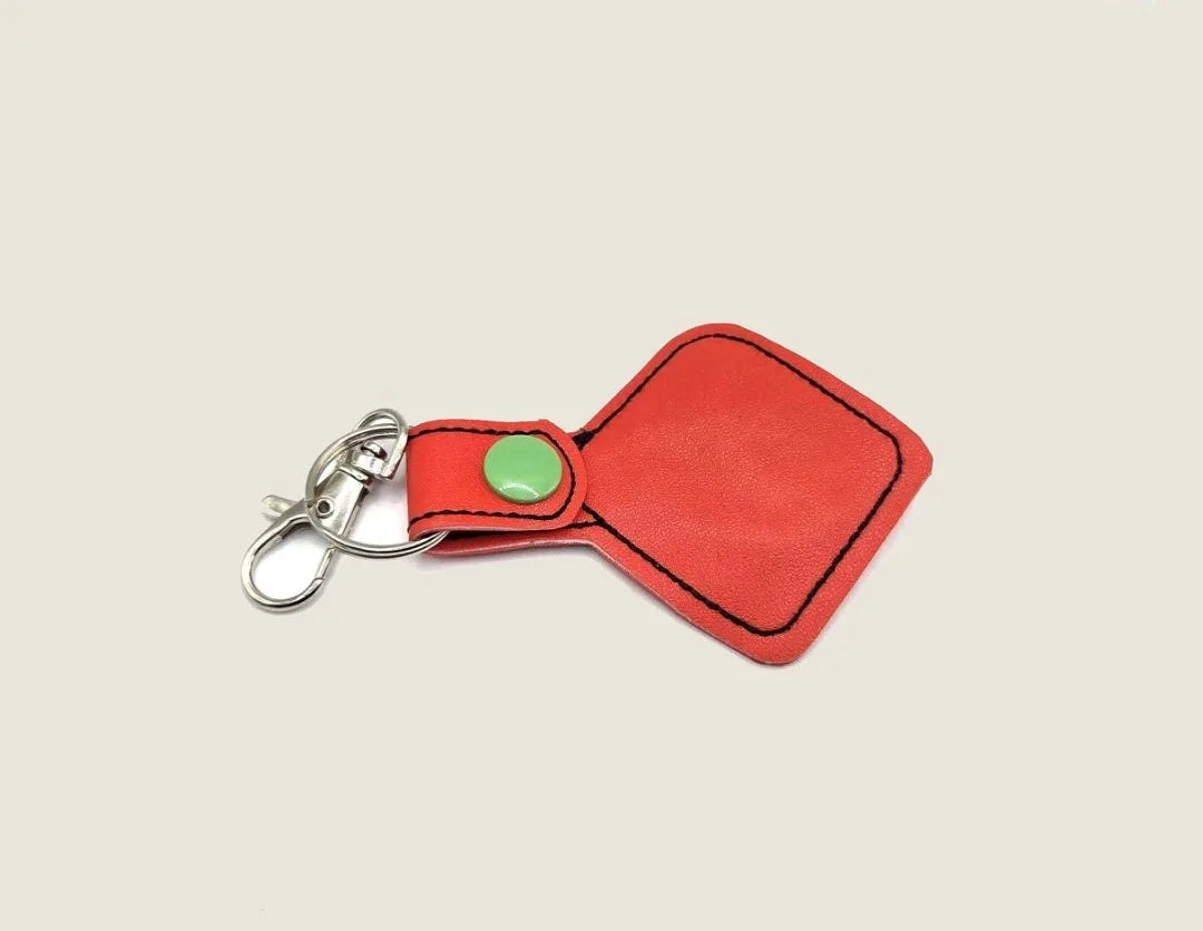Red leather Dice Keychain featuring a green snap button and sturdy metal clip, perfect for tabletop RPG enthusiasts.