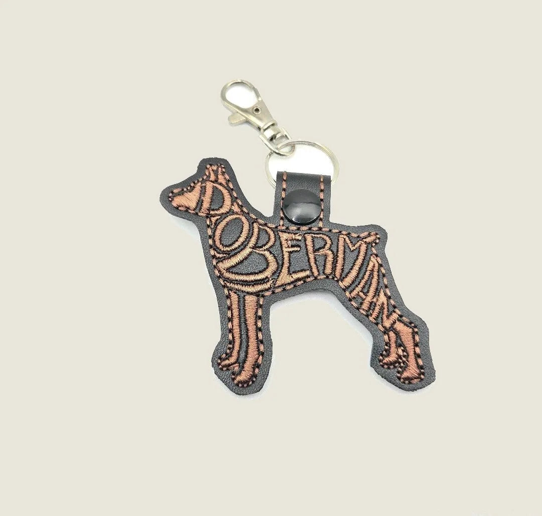 Embroidered Doberman keychain in black faux leather with copper stitching, featuring a swivel clasp for easy attachment.