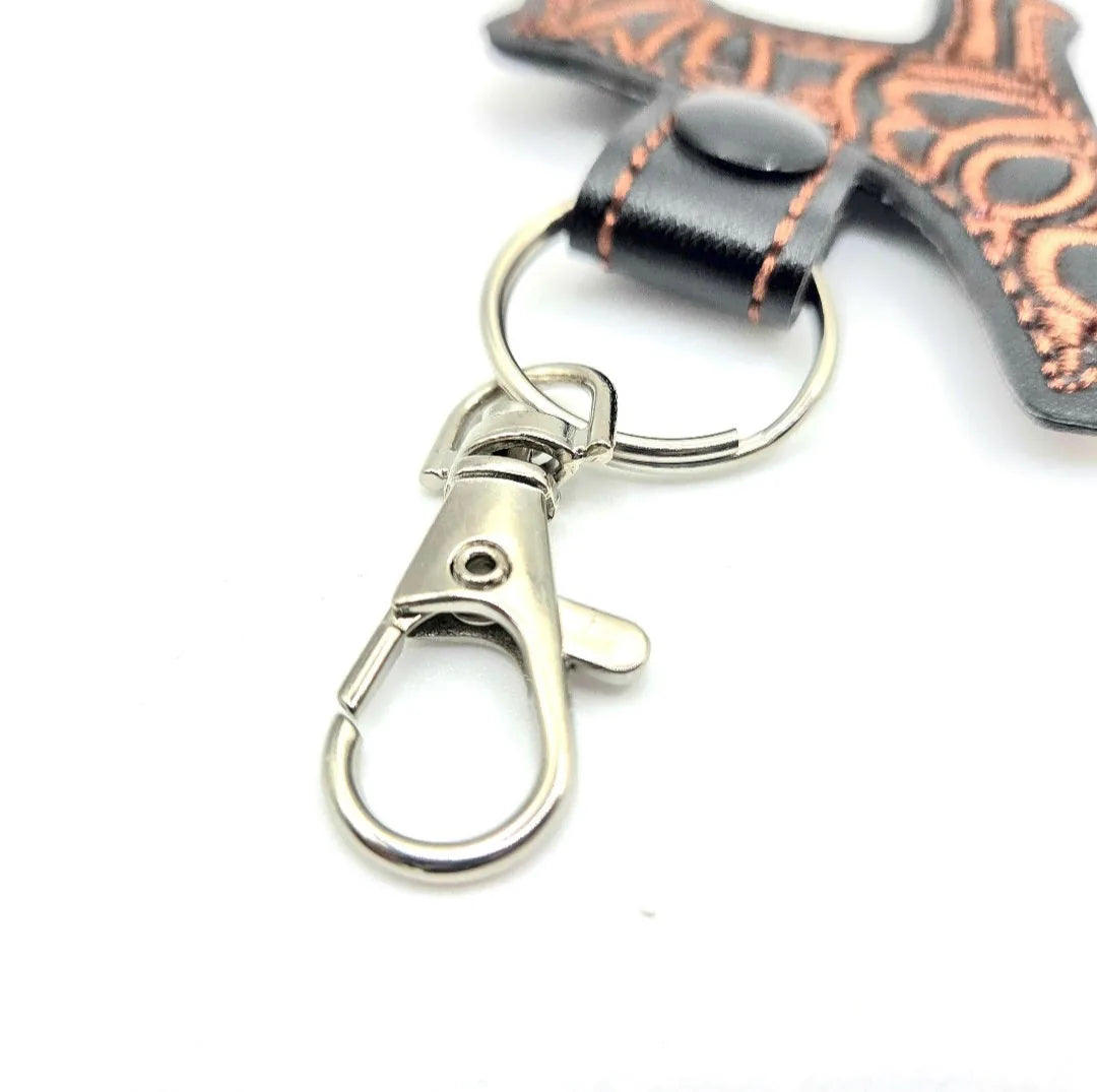 Metal swivel clasp and split ring attached to a black faux leather keychain with copper stitching detail.