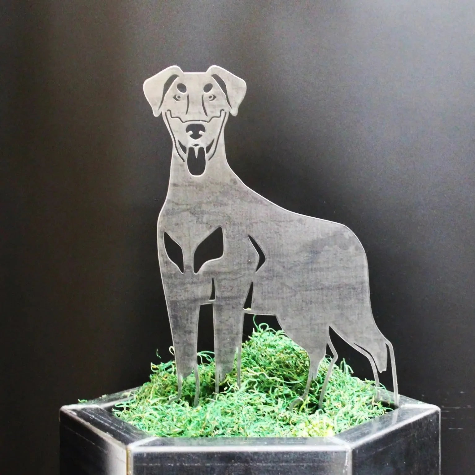 Doberman Pinscher metal silhouette in Corten steel, set in green moss, showcasing natural ear design for outdoor decor.