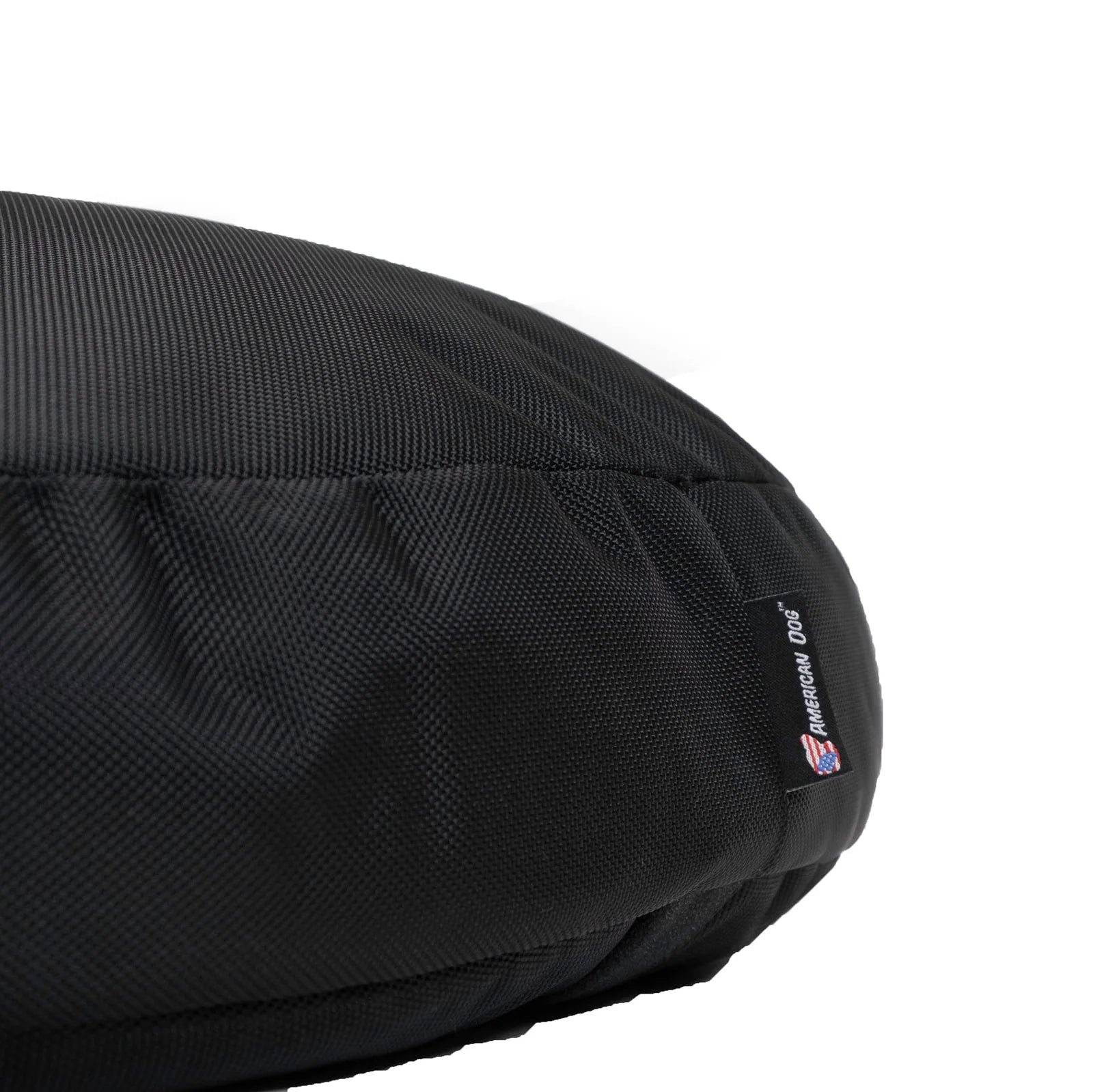 Durable black round dog bed made from rugged nylon, featuring a tag and textured fabric for heavy chewers.