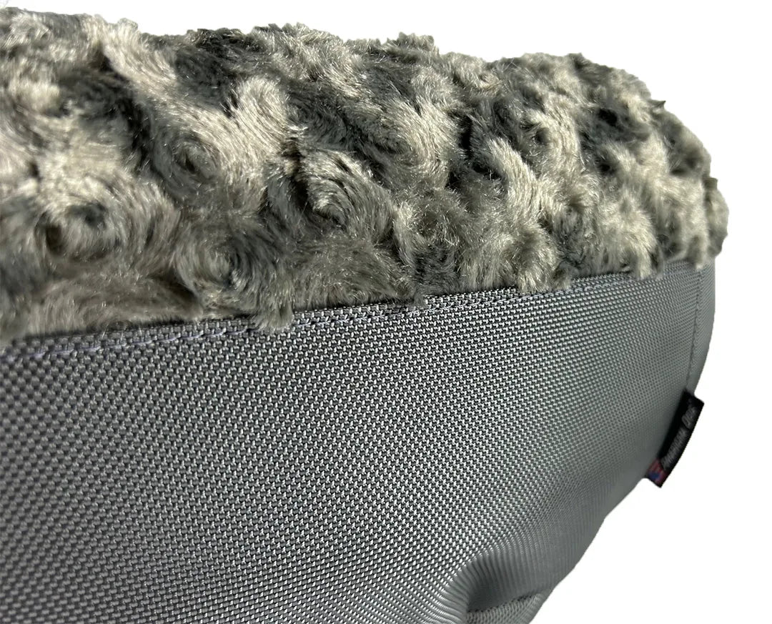 Round bolstered dog bed with soft gray Minky Rose Fleece and durable nylon ballistic material, featuring a plush texture.