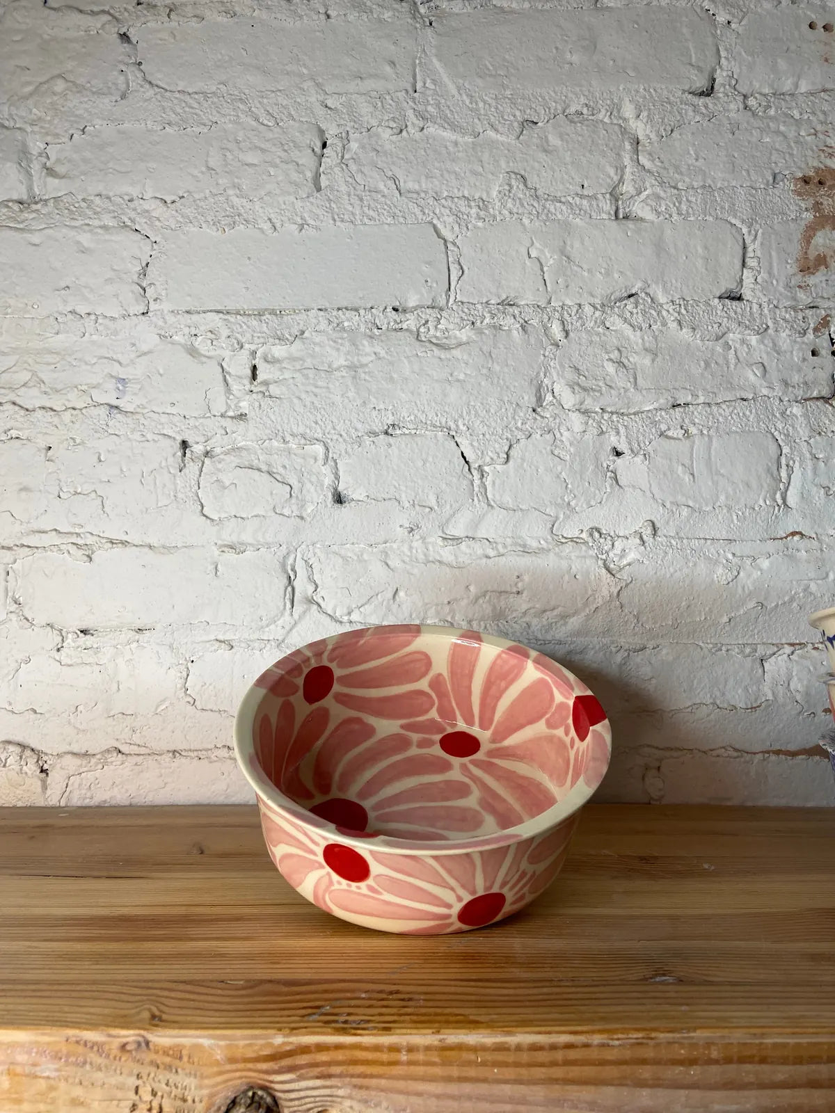 Hand-painted ceramic dog bowl featuring a pink floral design with red dots, perfect for stylish feeding.