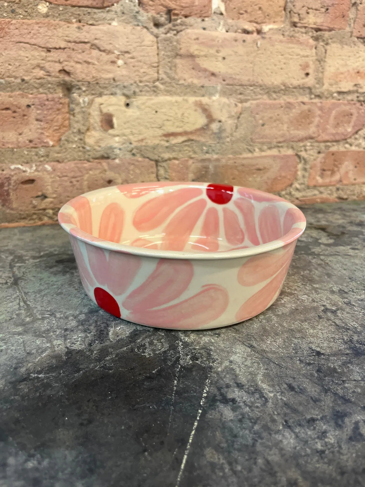 Hand-painted pink dog bowl with red floral designs, perfect for mealtime charm and style.