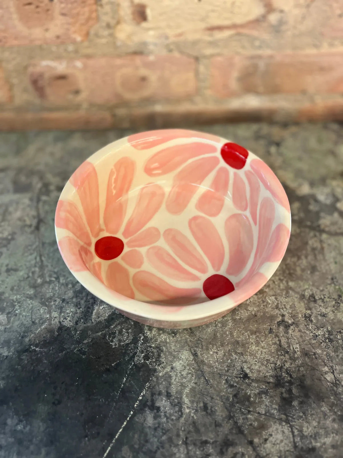 Hand-painted ceramic dog bowl in a pink flower design with red accents, perfect for stylish pet feeding.