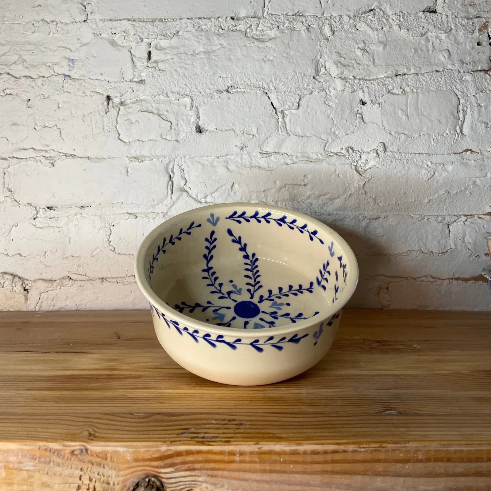 Hand-painted cream dog bowl with blue floral design, perfect for stylish pet feeding.