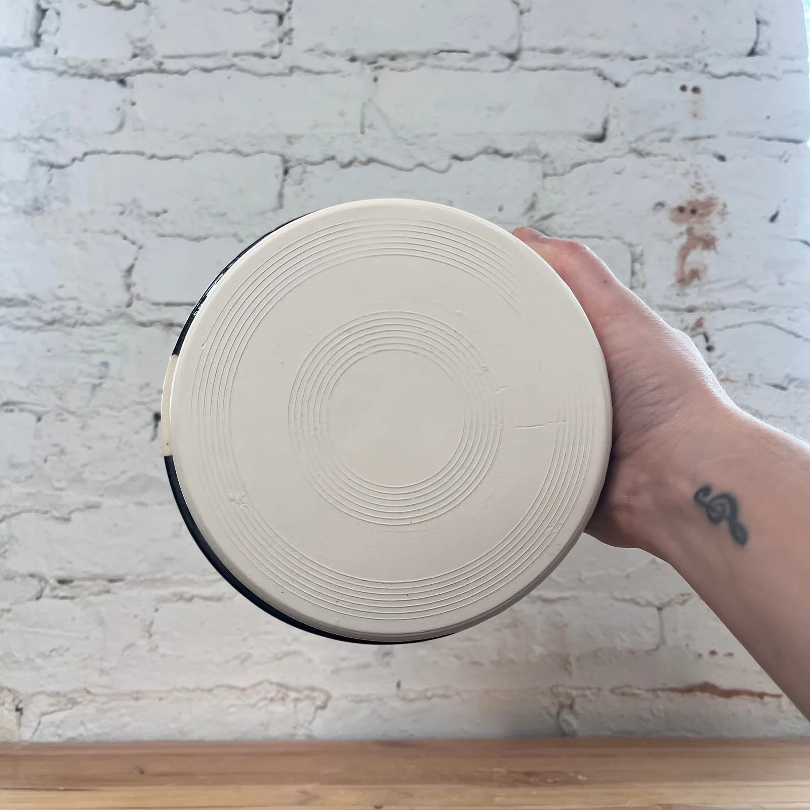 Handheld ceramic dog bowl showing a smooth cream surface with circular designs, ideal for thoughtful pet feeding.