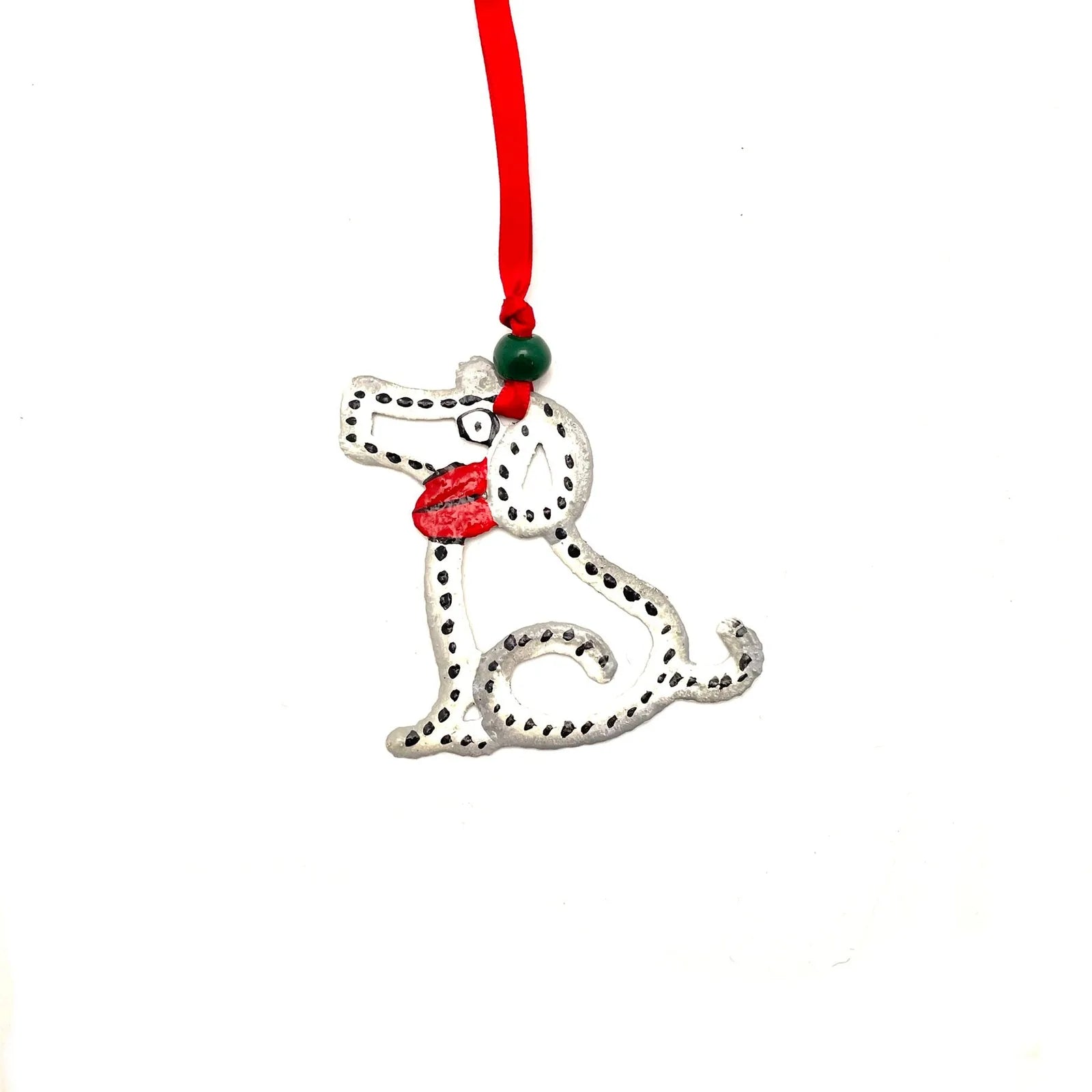 Handcrafted metal dog ornament with red and green accents, featuring a playful design in silver.