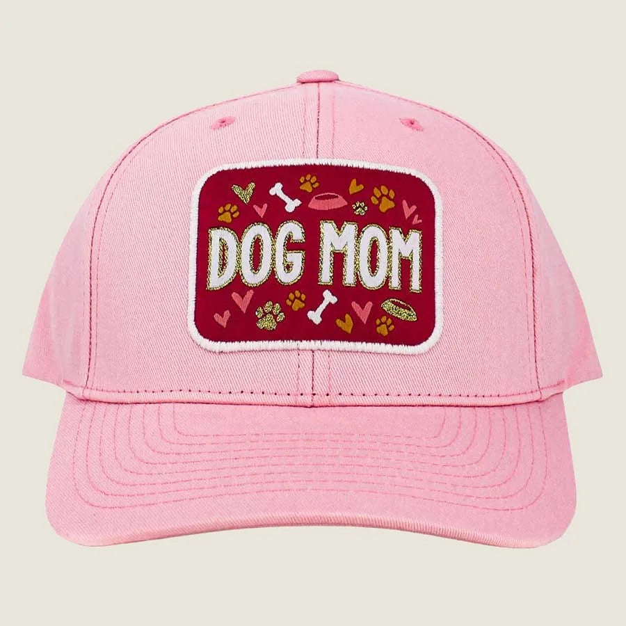 Pink baseball cap with "DOG MOM" embroidered on a red patch, featuring playful paw prints and hearts.