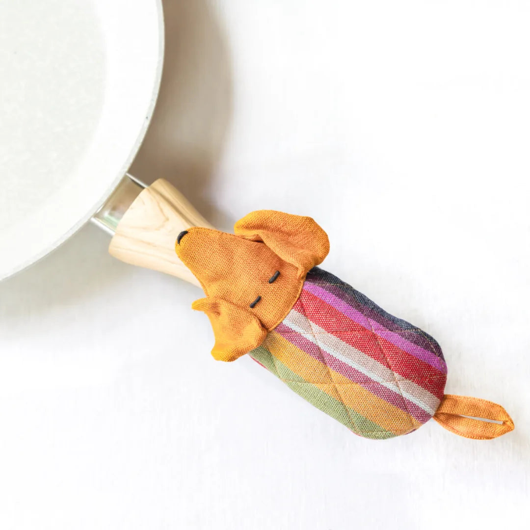 Handcrafted dog skillet handle holder in orange with colorful striped pattern, providing heat resistance for safe cooking.