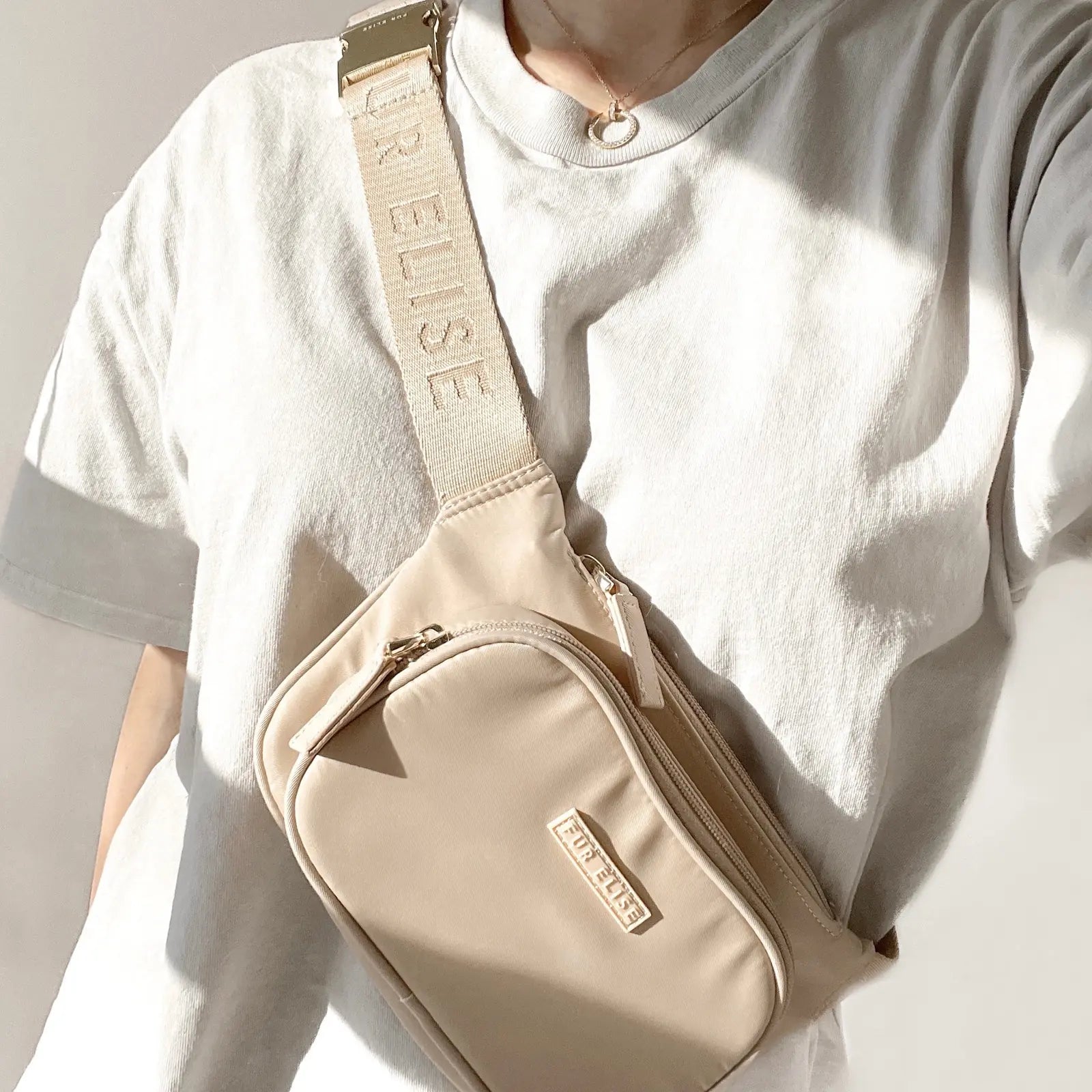 Lightweight sand-colored dog walking bag with adjustable strap and zippered pockets, worn across the body.