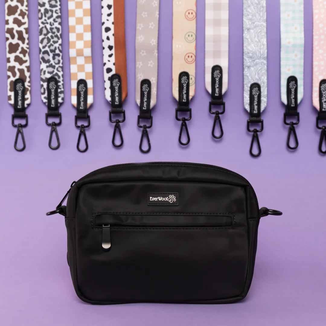 Compact black nylon dog owner essentials bag with a front zipper pocket on a purple background.