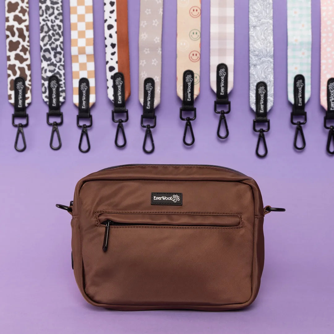 Brown waterproof fabric dog owner essentials bag with zippered pockets, displayed against colorful dog leash straps.