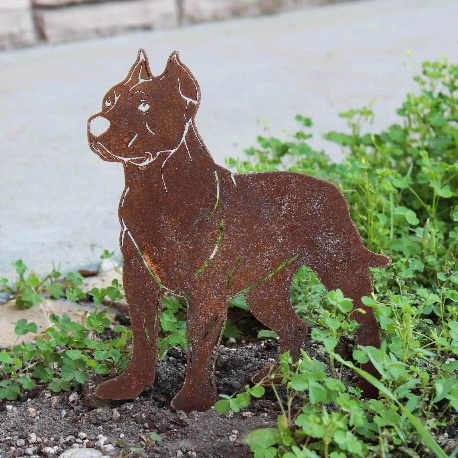 Dogo Argentino metal silhouette in rust finish nestled in greenery, perfect for outdoor decor.