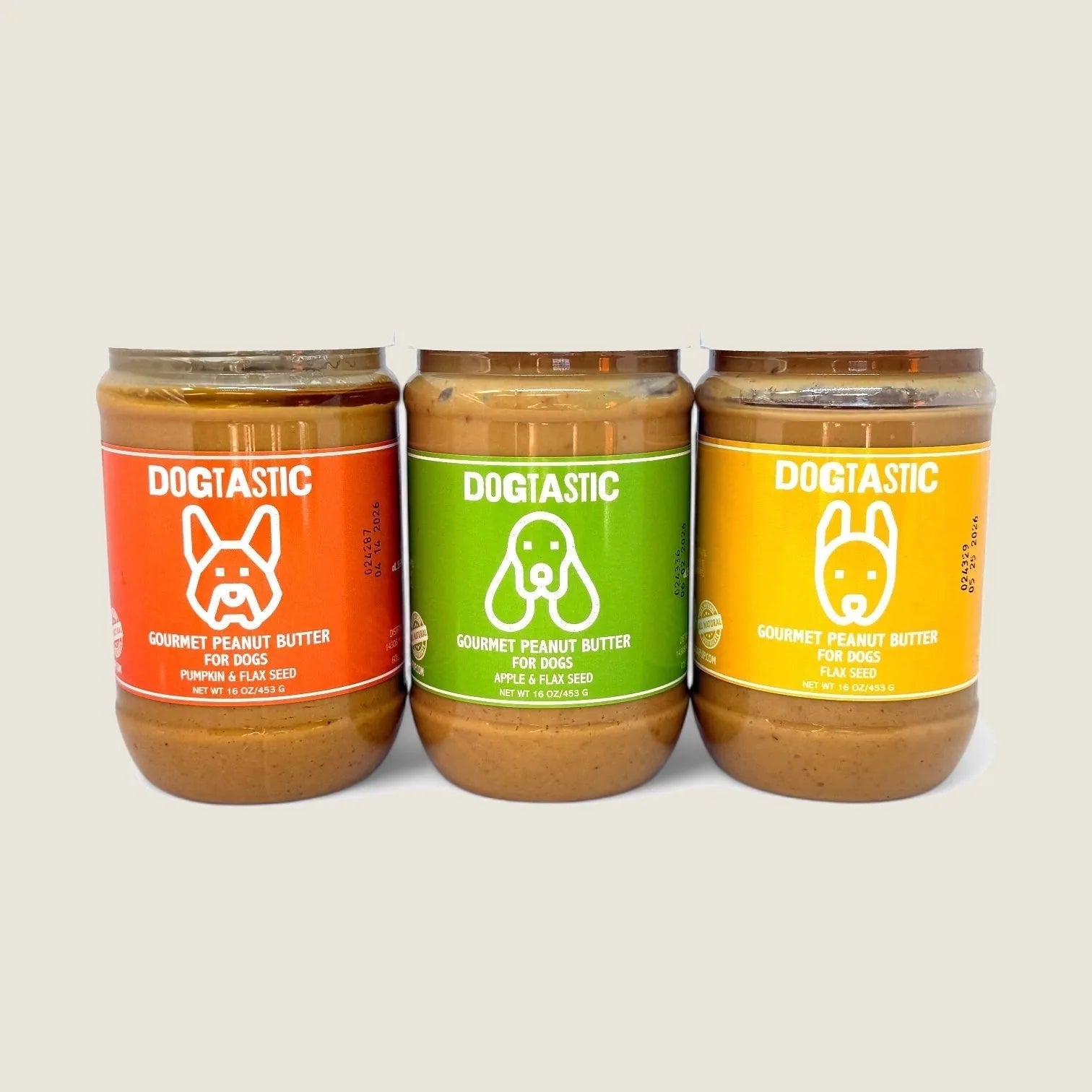 Three jars of Dogtastic Gourmet Peanut Butter for Dogs in vibrant orange, green, and red, labeled with flavors and dog gra...
