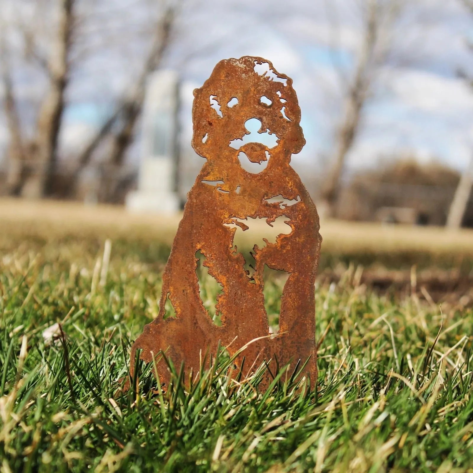 Rusty metal silhouette of a Doodle dog resting on green grass, showcasing intricate cut-out details. Perfect for outdoor d...