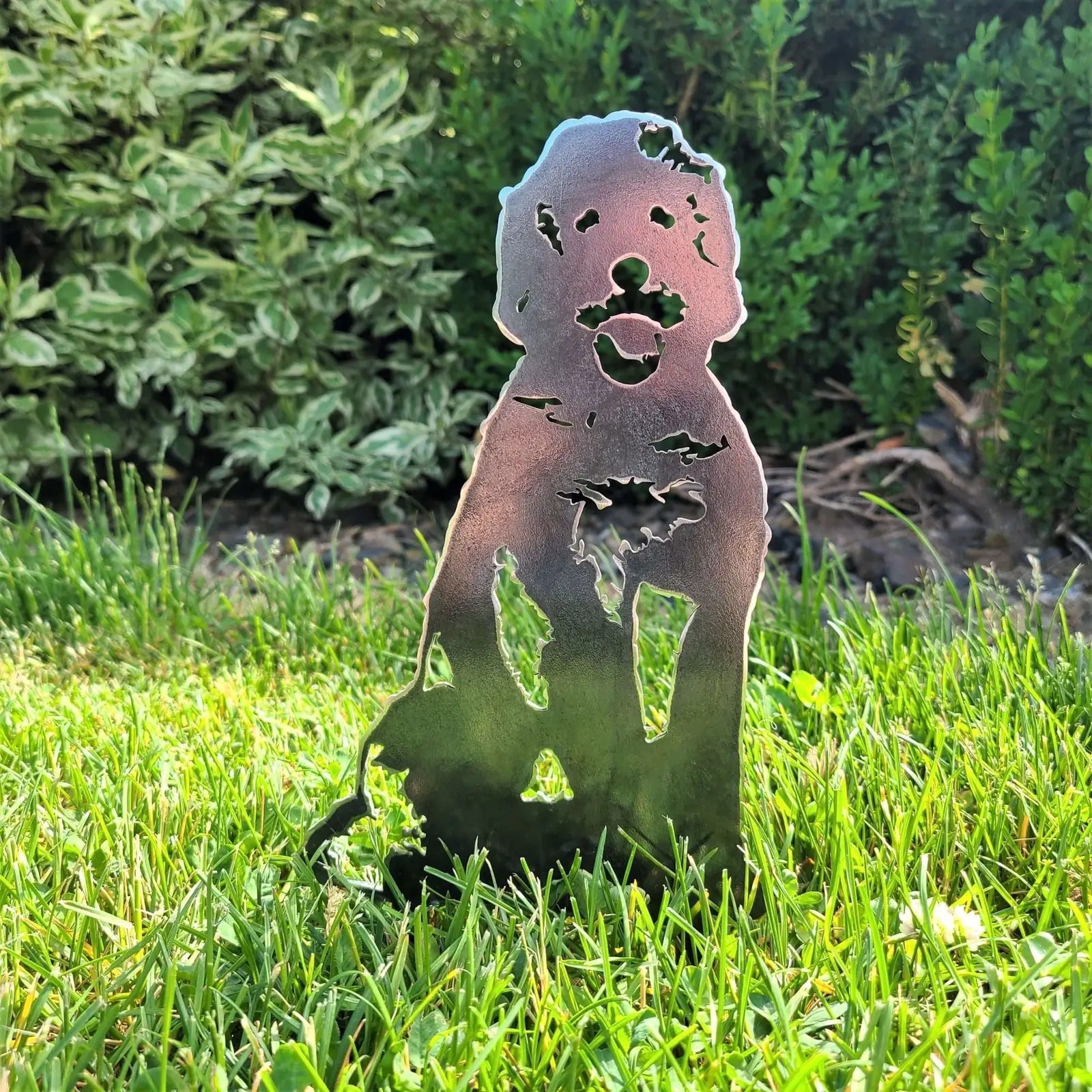 Corten steel Doodle dog silhouette standing in lush green grass, showcasing intricate cut-out details.